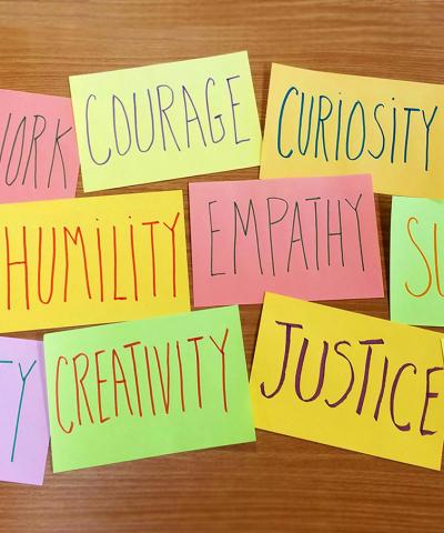 Inspiring words like courage, justice, empathy, on colorful sticky notes. 