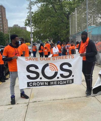 Save our Streets banner is displayed by two men at a march in Brooklyn.