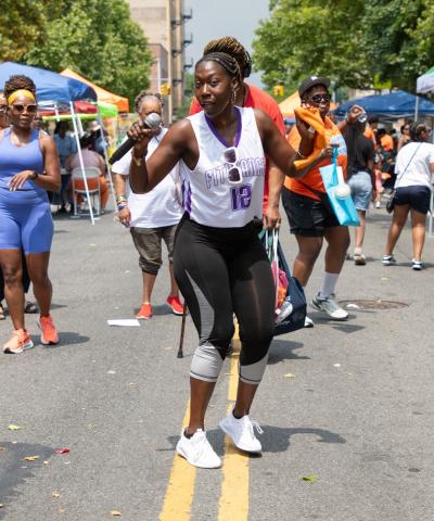 Woman leading a dance exercise outdoors at RISE's Revive, Thrive, 'n' Vibe block party in the Bronx