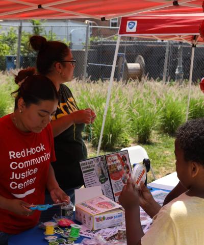 Staff from our Red Hook Community Justice Center tabling with art supplies and flyers for children and families at outdoor community event.