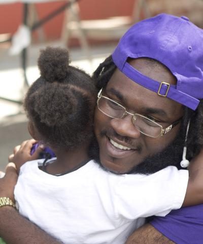 Child hugs Brownsville Community Justice Center staff member at local event.