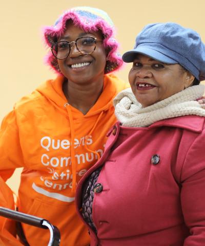 Queens Community Justice Center staff person and community member pose for a photo at the Justice Center's Thanksgiving giveaway with the Amazin' Mets Foundation.