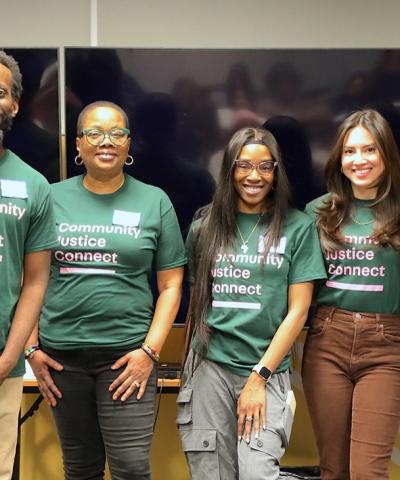 Seven people stand together in a row with green and pink Community Justice Connect shirts on