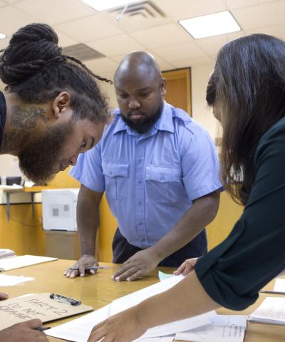 Three people leaning over a table reviewing court documents together in Newark Municipal Court