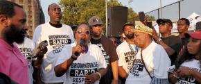 Brownsville Community Justice Center staff outside at an event; one of the staff is speaking into a microphone