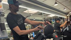 Barber giving a haircut to a young Black man at the Barbershop Factory in the Bronx.