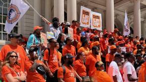 Our gun violence prevention teams stand alongside other Cure Violence staff dressed in orange with anti-violence placards and flags.