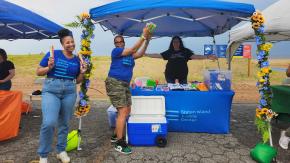 Our Staten Island Justice Center team poses at an outdoor table with pamphlets, water bottles, and cold snacks.