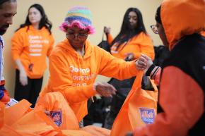 Queens Community Justice Center team member handing off a Thanksgiving turkey in Amazin' Mets bag.