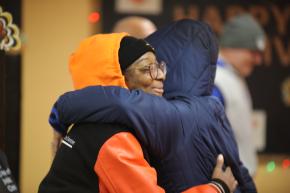 Staff and community member hug at the Queens Community Justice Center's Thanksgiving giveaway.