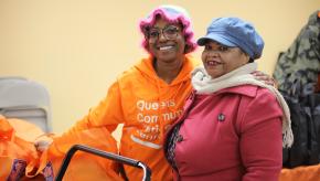 Queens Community Justice Center staff person and community member pose for a photo at the Justice Center's Thanksgiving giveaway with the Amazin' Mets Foundation.