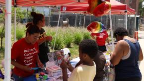 Staff from our Red Hook Community Justice Center tabling with art supplies and flyers for children and families at outdoor community event.