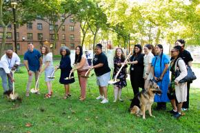 A group of people hold shovels at unveiling of the Castle Hill Houses' new dog park and BBQ area.