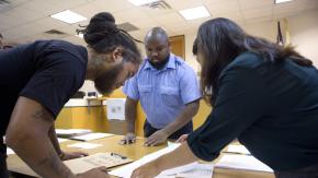 Three people leaning over a table reviewing court documents together in Newark Municipal Court