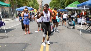 Woman leading a dance exercise outdoors at RISE's Revive, Thrive, 'n' Vibe block party in the Bronx